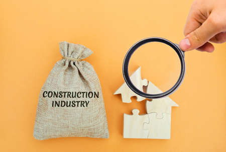 A bag with the word Construction industry and a house of puzzles. Real estate building concept. Planning, financing, and design. Investmentsの写真素材