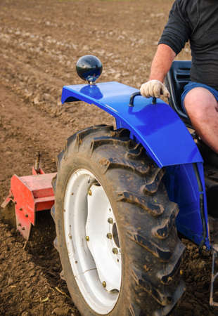 The tractor is cultivating the soil in the farm field. Loosening and mixing. Softening of the soil...