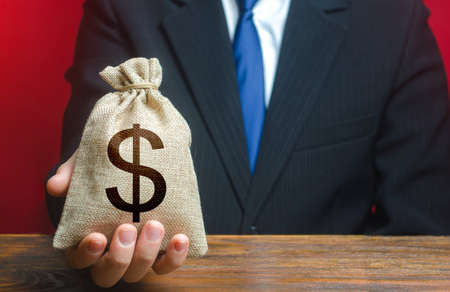 Man gives a dollar money bag. Loan issuance. Financial support, leasing. Earnings and profits. Investments, financing Lobbying. Accounting and accounting, tax payment. Funding, charity. Philanthropyの写真素材