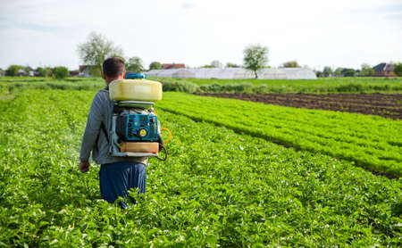 Kherson oblast, Ukraine - May 22, 2021: Farmer sprays pesticides on plantation. Use chemicals for plant protection from insects and fungal infections. Agriculture industry. Pesticides and fungicides.のeditorial素材