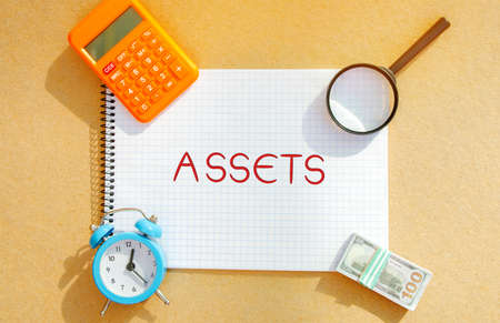 Notebook with an inscription Assets. Financial accounting. Money and finance. Cash equivalents, certificates of deposit. Dollars, magnifying glassの写真素材
