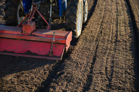 The tractor cultivator breaks up and mixes the soil, giving it softness and moisture for further cutting into rows. Small farms. Work in the agricultural industry. Agricultural machineryの写真素材