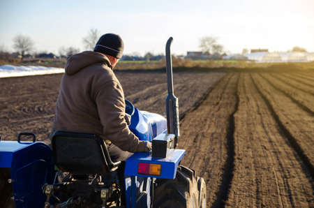 The tractor is cultivating the soil in the farm field. Farming. Agriculture agribusiness. preparing for cutting rows for the next sowing season in the spring. Softening and improving soil qualities.の写真素材