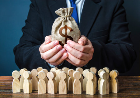 Businessman holds out a dollar money bag to the crowd. Official. Providing money, paying salaries and grants. Staff maintenance. Financial support. Tax collection. Compensation payments. Share profit.の写真素材
