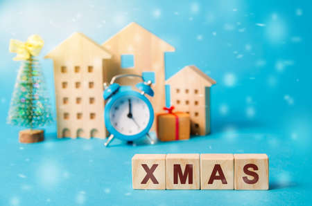 Wooden blocks with the word Xmas, miniature houses, clock and a Christmas tree. New Years...