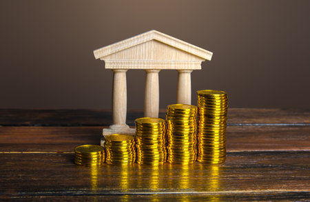 Bank building and increasing stacks of coins. Profitability of deposits and favorable rates for depositors, loyalty programs. Income growth. Increasing taxes collected. Budgeting. Monetary policy.の写真素材