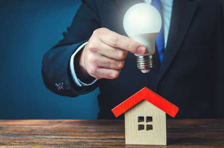 Glowing light bulb over the house. smart eco house. Electricity supply. Timely payment of bills. Utilities companies. ideas for home. innovations and technologies. energy efficiency.の写真素材