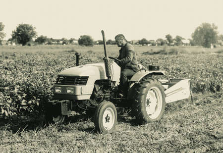 A farmer on a tractor is working on a farm field. Agroindustry and agribusiness. Agricultural sector of the economy. plant food production. Machinery and equipment.の写真素材