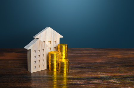 Houses and golden coins. Savings on household bills. Energy efficiency and energy saving. Profit from investment in housing. Municipal budget for the maintenance of buildings. price cost estimateの写真素材