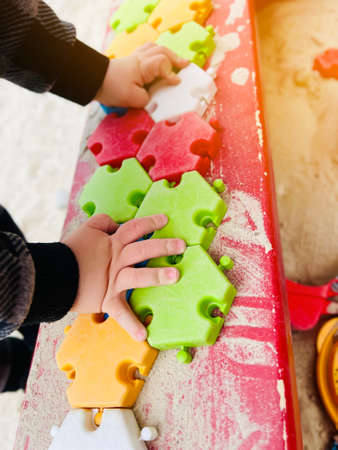 The child plays in the sandbox with colorful puzzles. selective focus