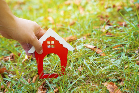 Miniature wooden house in the hands of a man outdoors. real estate concept. Eco friendly home. Buying a housing outside the city. red roof. selective focusの写真素材