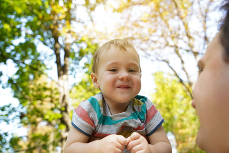 Dad plays with his little son in the park outdoors. family time. Happy smiling people. Boy of one...