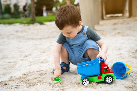 Little cute toddler boy 2.5 years old plays in the sandbox on a sunny summer day. Outdoor creative...