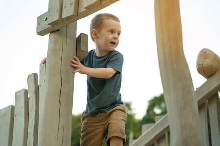 A cute curious toddler boy of two or three years playing on a wooden playground outside. Active games and entertainment for children. summer day. selective focusの写真素材