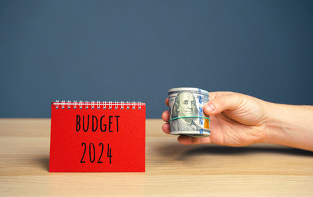 Budget 2024. Financial management in company. Setting goal, target concept. Plans and tasks. business and finance concept. Company's annual income statement. Note, dollars in the hand of a businessmanの写真素材