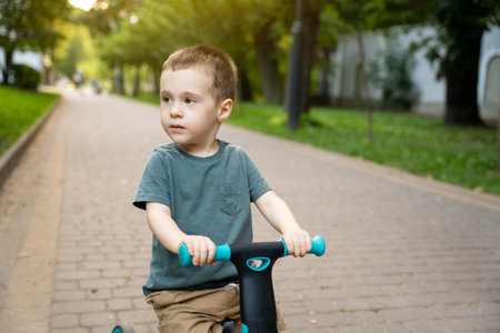A cute toddler boy of two or three years old rides a bicycle or balance bike in a city park on a sunny summer day. Toddlerhood and childhood concept. selective focusの写真素材