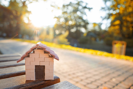 A miniature house stands on a bench in the park in the light of the setting sun. Real estate, affordable housing and mortgage lending concept. Sale, purchase and rental of apartments. Selective focusの写真素材