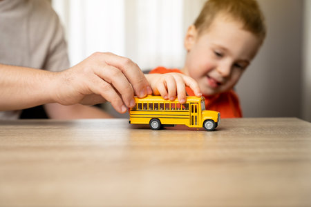 Happy smiling toddler boy playing with yellow car with his dad. Spending time with children. The...