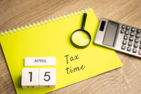 April 15 - tax time concept. Taxpaying, business and finance. Notes, magnifying glass and calculatorの写真素材