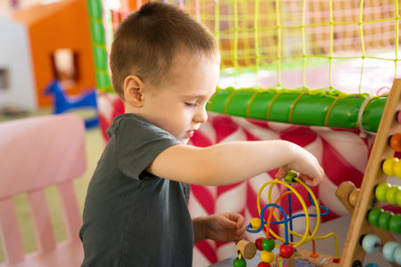 Toddler boy plays with educational wooden toy in children's playroom. Ð¡hildhood concept. Selective focusの写真素材