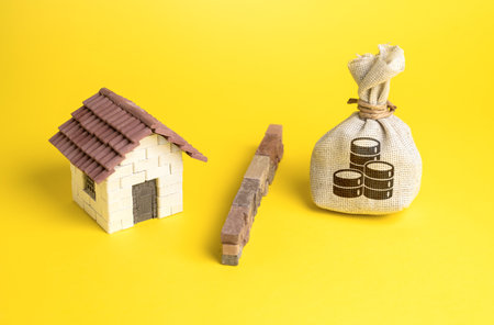 The house and the money bag are separated by a barrier. Investment as a threat to create a market bubble. The influx of capital. High levels of debt. Stop overheating real estate market.の写真素材