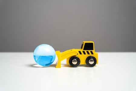 Bulldozer pushes planet earth blue globe. Human impact on the environment, prompting reflection on environmental concerns and the need for sustainable practices.の写真素材