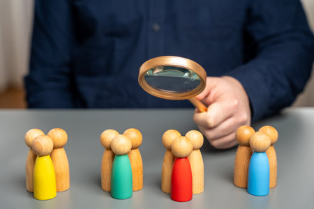 The concept of market segmentation. Target audience, customer care. Market group of buyers. Customer relationship management. Businessman looking through a magnifying glass at figurines of peopleの写真素材