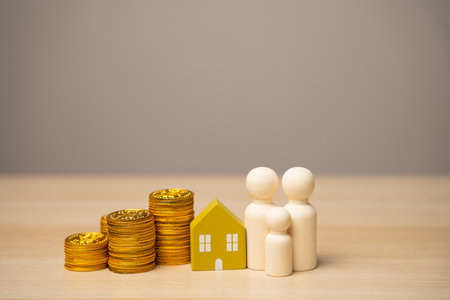 Miniature figures of the family stand near the house and coins. The concept of family budget, mortgage lending and money in the family. Real estate and housingの写真素材