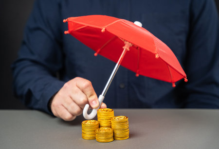 Businessman holding umbrella over stack of coins. Financial risk insurance concept. Investments, deposits and loans. Risks and monetary transactions. Insurance contract and damage compensationの写真素材
