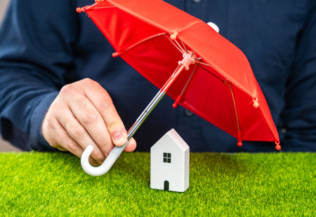 Man covering house with red umbrella. Insurance concept. Be prepared for unforeseen events. Repairs or rebuilding in the event of a covered loss.の写真素材