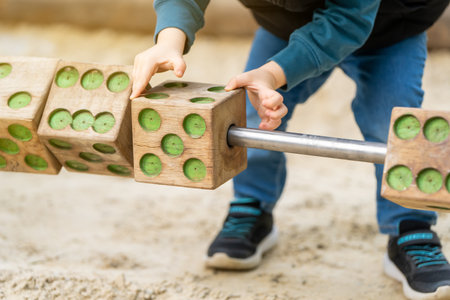 Cute toddler three years old boy is playing on the playground with wooden blocks. Children's games....