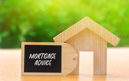Mortgage advice concept. Professional guidance provided to help individuals choose, obtain, and manage home loans. Real estate. Wooden house with a noteの写真素材