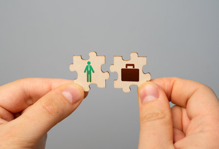 Two puzzles in hands with a symbol of a worker and work in the form of a suitcase. Finding the best job offer. In search of work and earnings.の写真素材