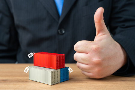 Businessman showing thumbs up and containers with price tags. Selling containers and confiscated cargo. Marking up duties and protective tariffs on imports. Profit from trade.の写真素材