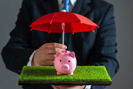 Businessman protects piggy bank with red umbrella. Savings insurance. Risk management, insurance coverage, investment safety, wealth preservation, and economic stability.の写真素材