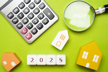 Wooden blocks 2025 and houses. Family budget planning for next year. Investments, plans, savings. Mortgage rates. Real estate concept. Magnifying glass and calculator. Flat layの写真素材