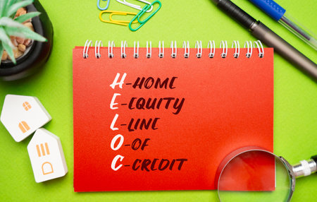 Heloc concept - Home equity line of credit. A line of credit extended to a homeowner that uses the borrowers home as collateral. Business and finance. Miniature houses, magnifying glass and notepadの写真素材