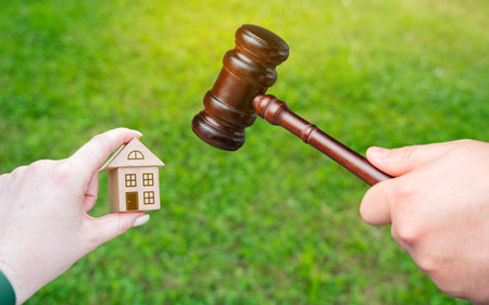 Judge's gavel near miniature wooden house outdoors. Real estate court decisions. Property inheritance litigation. Establishment of ownership.の写真素材