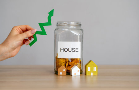 A glass jar with coins and the inscription House and an arrow pointing up. Growing demand in real estate, construction rates and trends. Rising housing prices.の写真素材