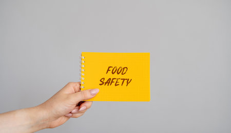 Food Safety concept. A method of handling, preparing, and storing food in ways that prevent foodborne illness. A woman holds a note in her hands with the word.の写真素材