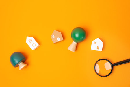 Houses, trees and magnifying glass an orange background. House searching concept. Home appraisal. Property valuation. Choice of location for the construction. Search for housing, apartments. flat layの写真素材