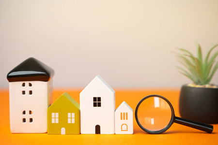 Magnifying glass and houses on an orange background. House searching concept. Home appraisal. Property valuation. Choice of location for the construction. Search for housing, apartments.の写真素材