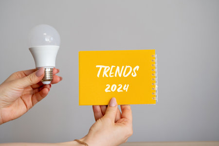 Notebook trends 2024 and lamp in hands. The concept of searching for new ideological trends and tendencies. Exclusive trend. Popular and relevant topics.の写真素材