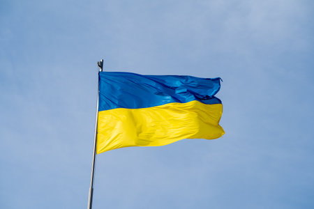 Ukraine flag, national symbol fluttering in blue sky. Large yellow blue Ukrainian state flag