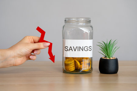 Money jar with savings and arrow pointing down. Concept of budget, income and finance reduction. Financial crisis and inflationの写真素材