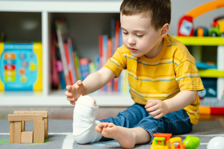 A little toddler boy holds his leg in a cast with his hands. Fracture of a foot and finger in children. Human healthcare and medicine concept. Bandageの写真素材