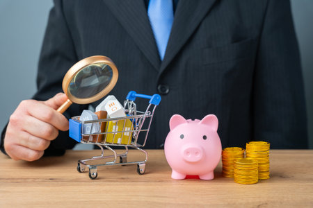 Real estate market concept, sale and purchase of housing. Rent of apartments and houses. Real estate agent. Businessman and houses in a supermarket cart with a piggy bank.の写真素材