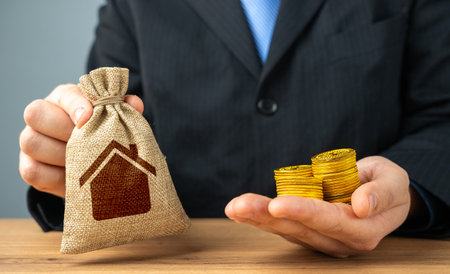 Businessman holding a bag with a house symbol and money coins. Sale of building permits. Housing stock, fees and payments for maintenance and repairs.の写真素材