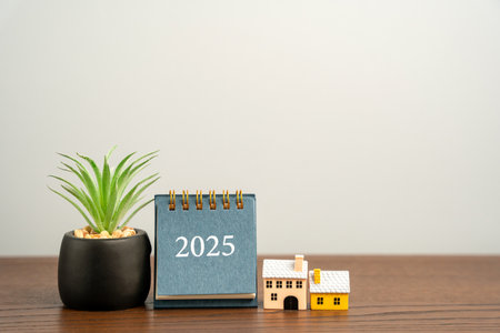 Calendar 2025, houses and succulents on a table. Beginning of a new year. Plan, planning and...