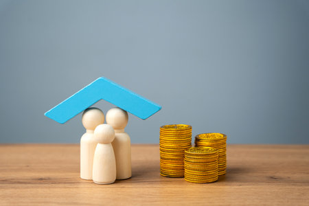 Property, home or health insurance concept. Family figurine under blue roof and coinsの写真素材